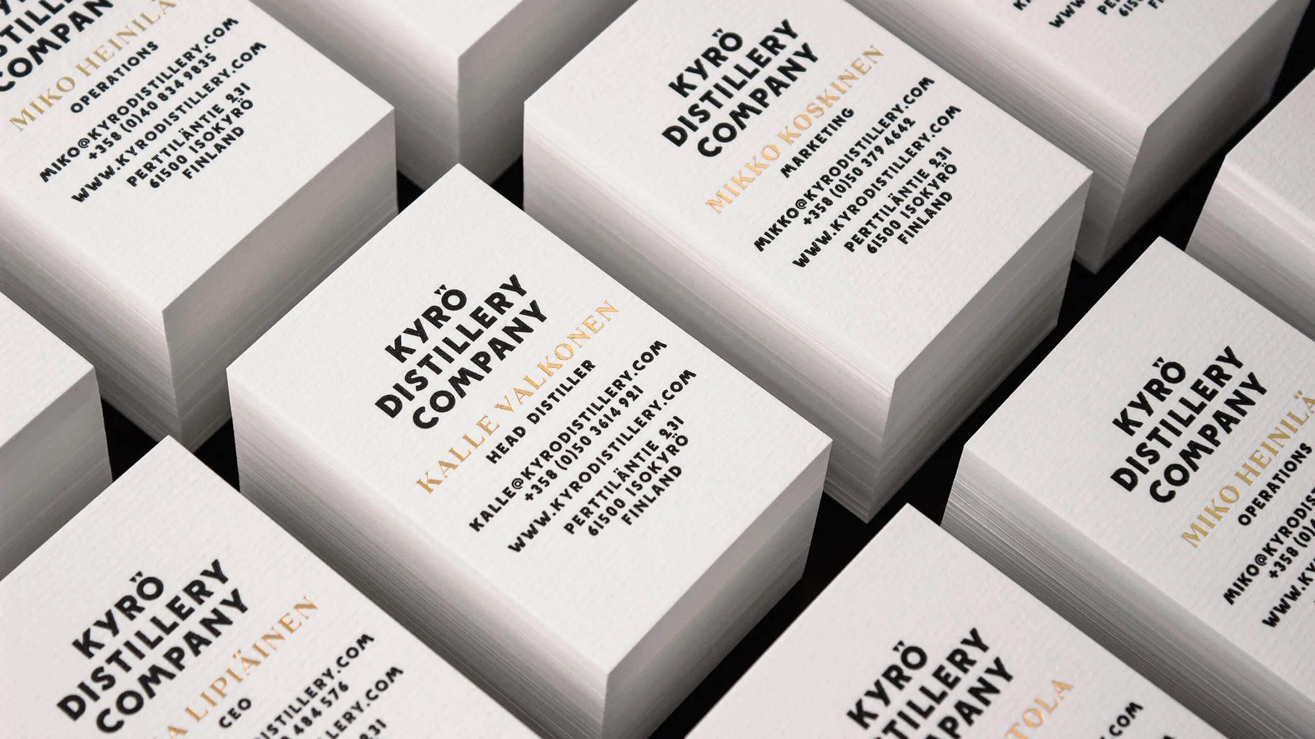 Kyrö Distillery Company business cards stacked in a grid, featuring bold black typography and gold foil names on white stock.