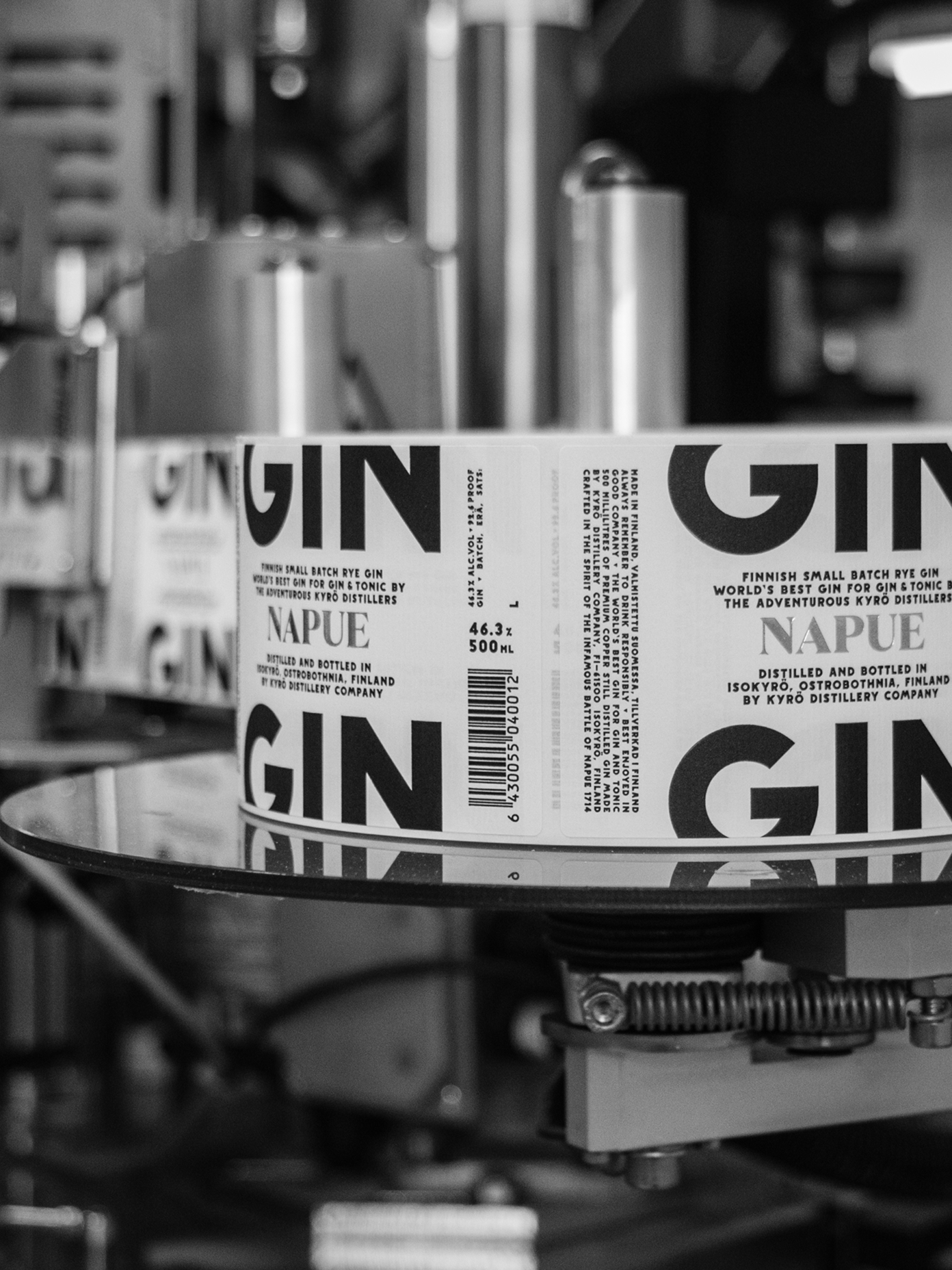 Kyrö Distillery Napue Gin bottle labels on a production line machine, showing bold typography and Finnish small batch rye gin branding.