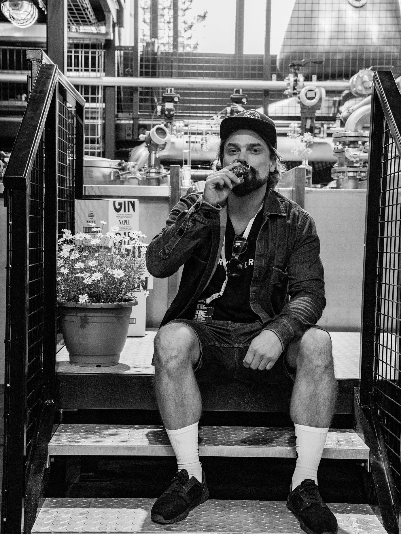 A man sits on metal stairs at Kyrö Distillery, in black and white.