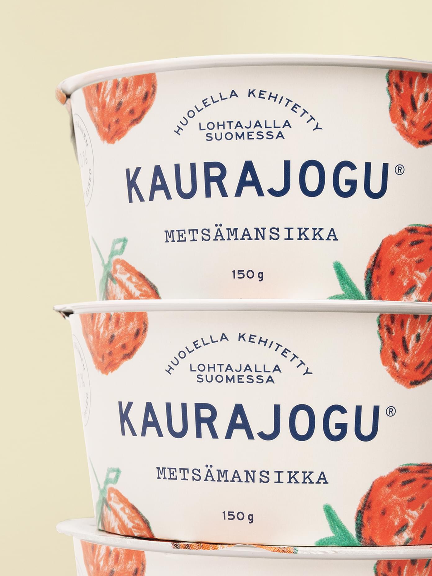 Two stacked Kaurajogu oat yogurt cups in wild strawberry flavour, featuring illustrated fruit on cream packaging.