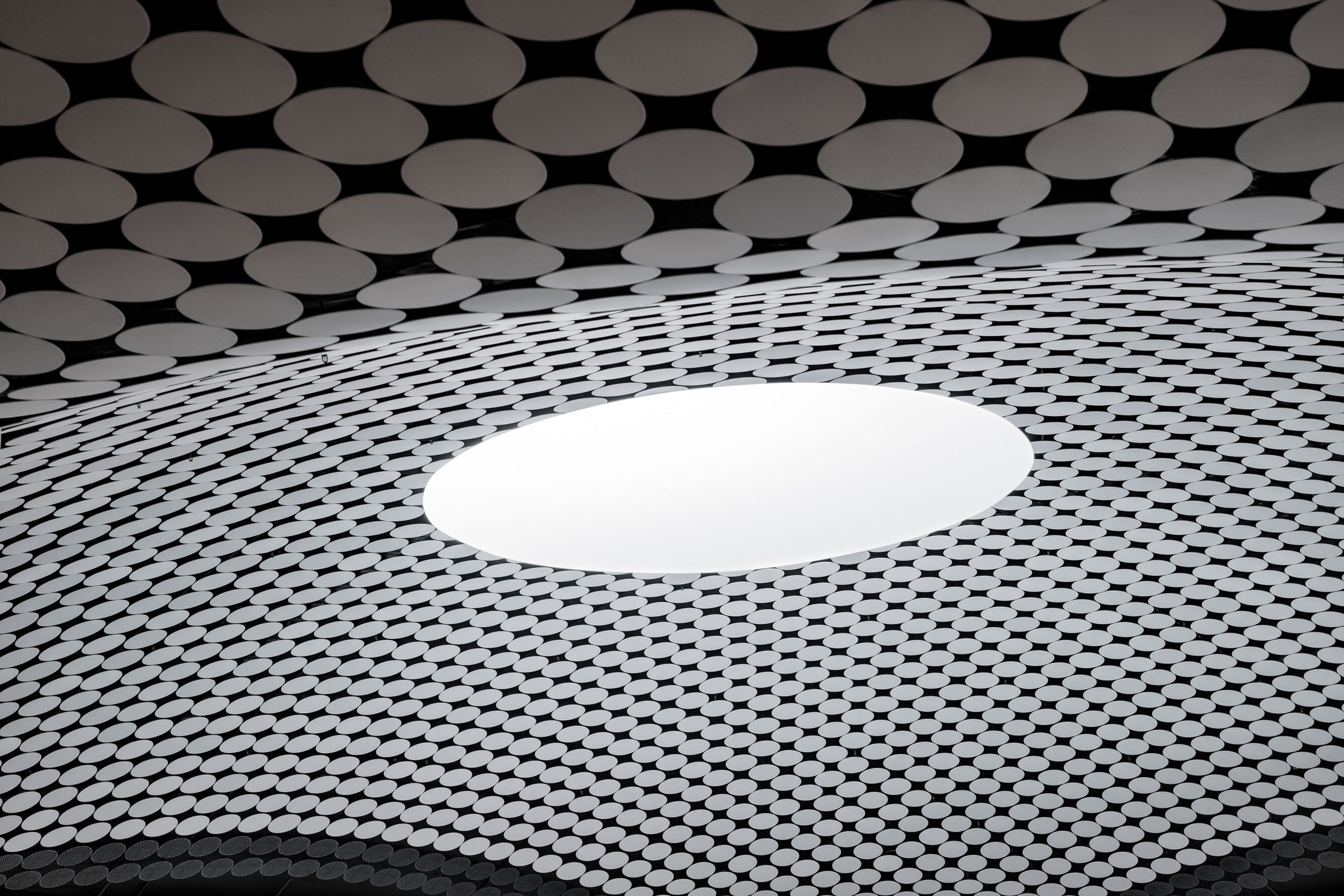 Close-up of Amos Rex's tessellated dome surface with a circular skylight opening to daylight.
