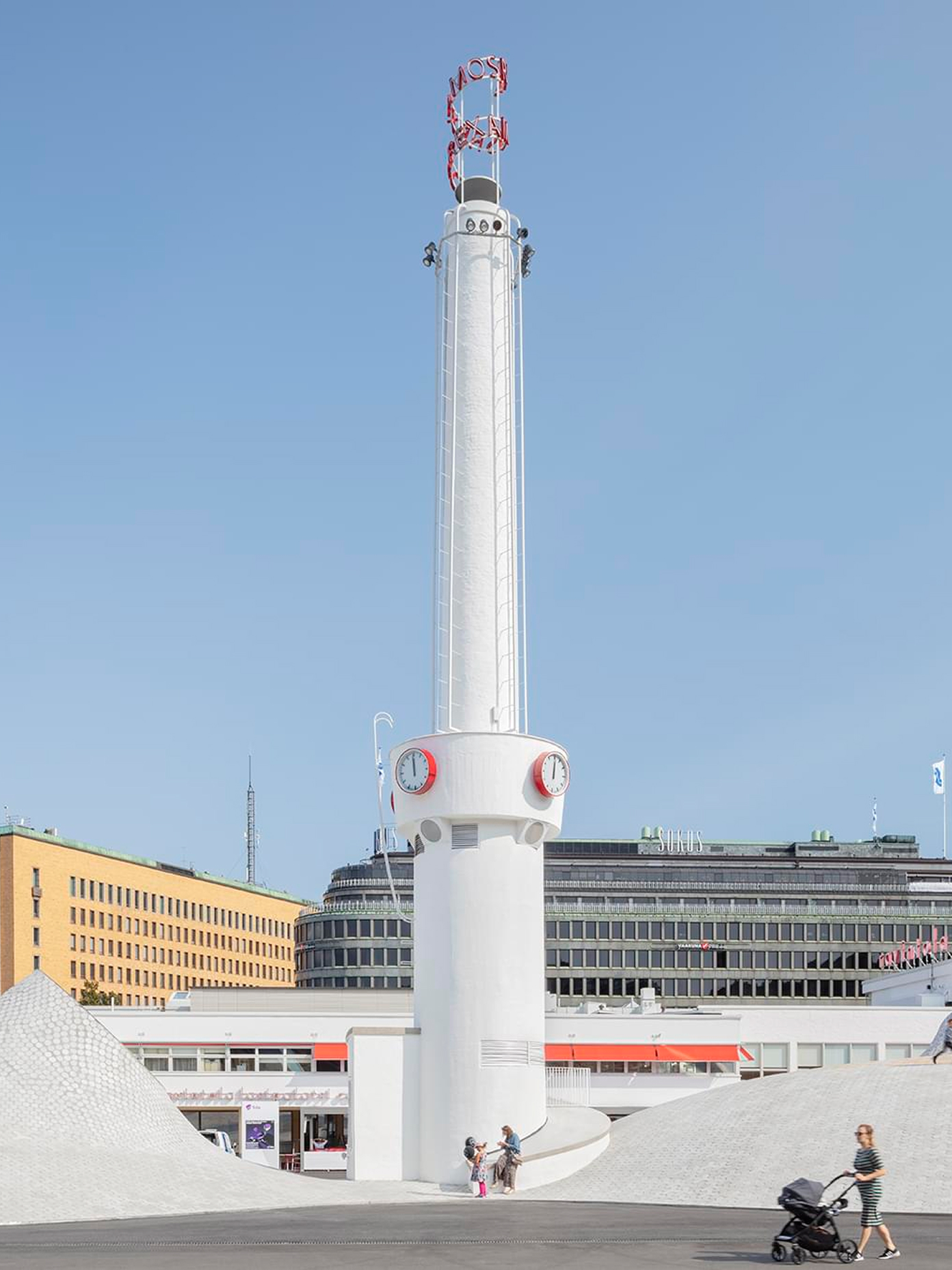 Lasipalatsi tower with clock faces and neon signage rising above Amos Rex's white domed rooftop in daylight.