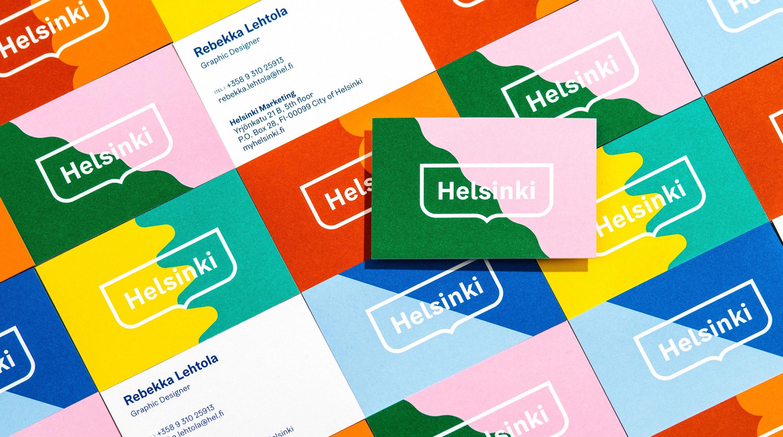 Grid of colorful Helsinki business cards featuring the logo, with one card showing a graphic designer's contact details.