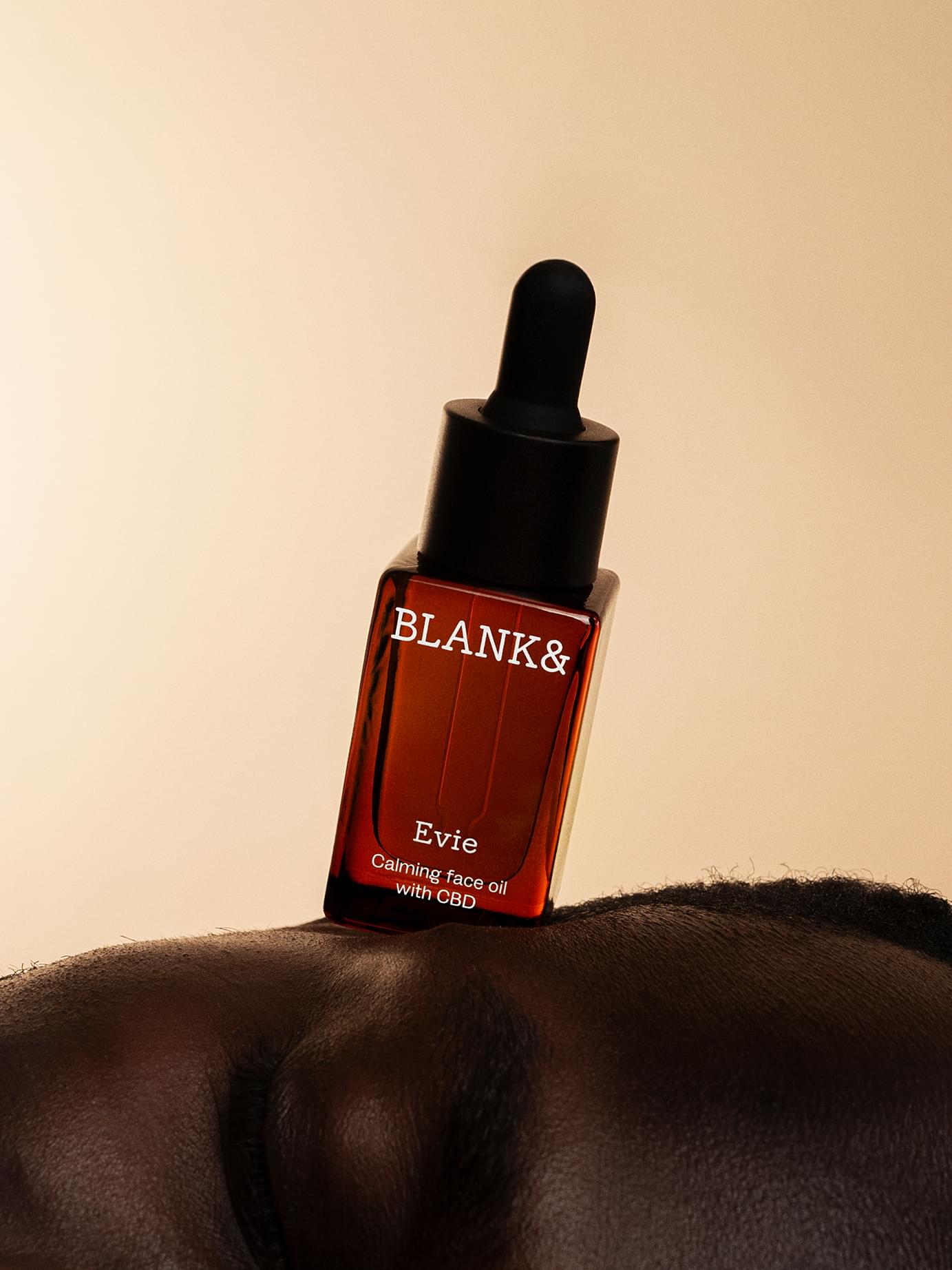 Blank& Evie calming face oil with CBD in amber dropper bottle balanced on a model's forehead.