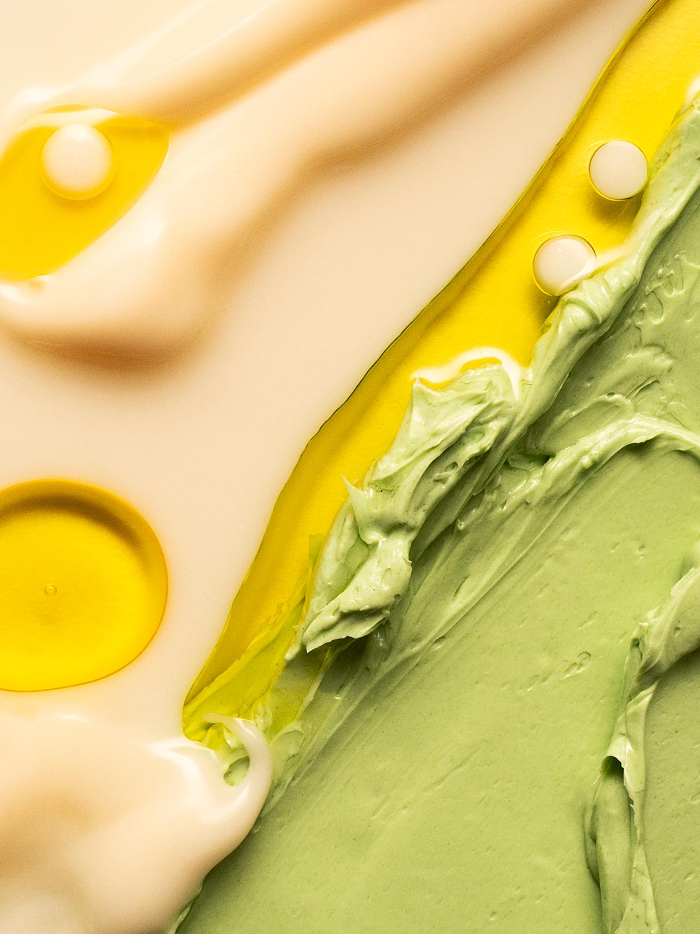 Close-up smear of cream, green, and yellow skincare textures with droplets, from Blank& branding by Werklig.