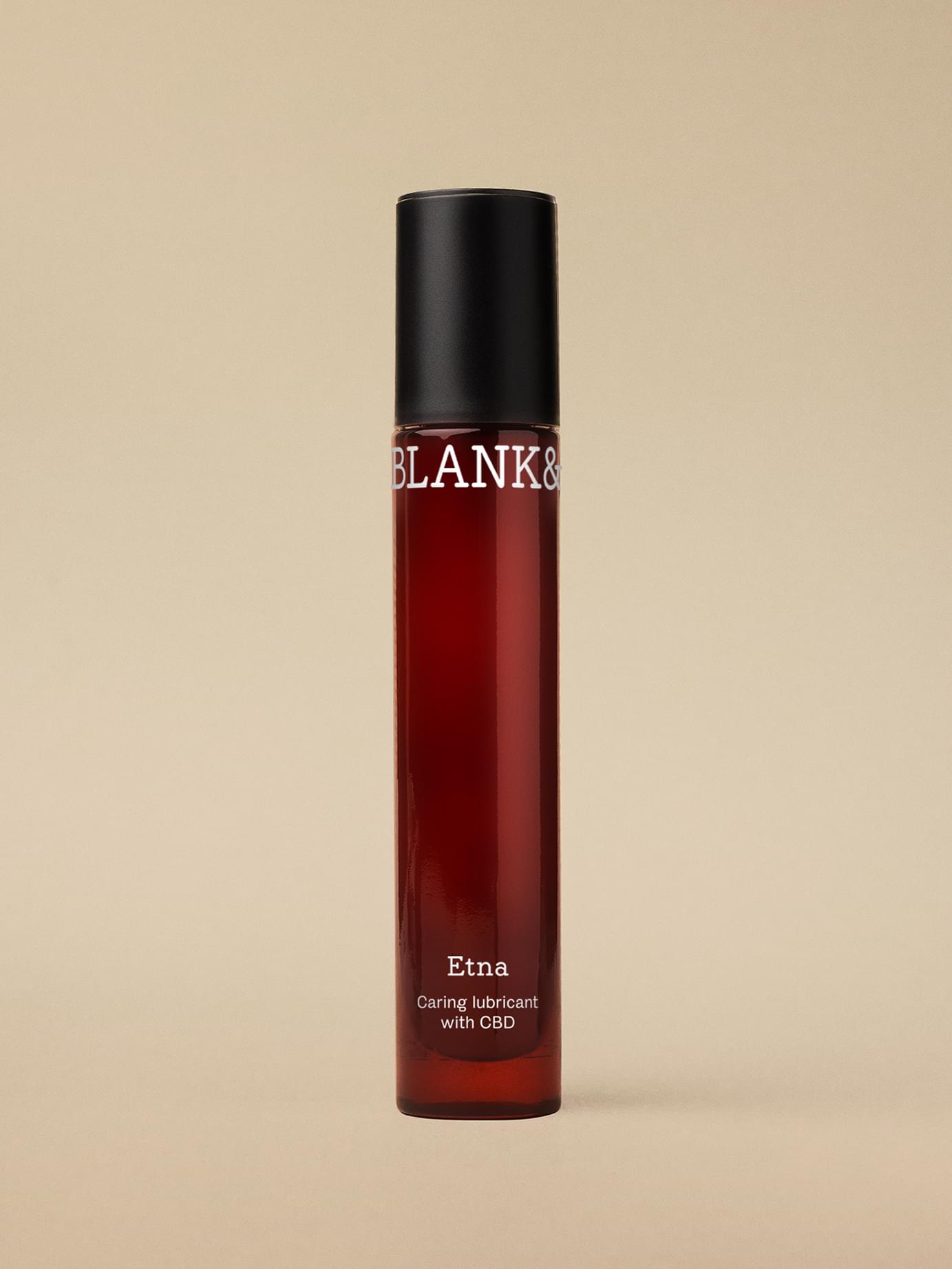 Blank& Etna CBD caring lubricant in a tall dark amber glass bottle with black cap against a warm beige background.