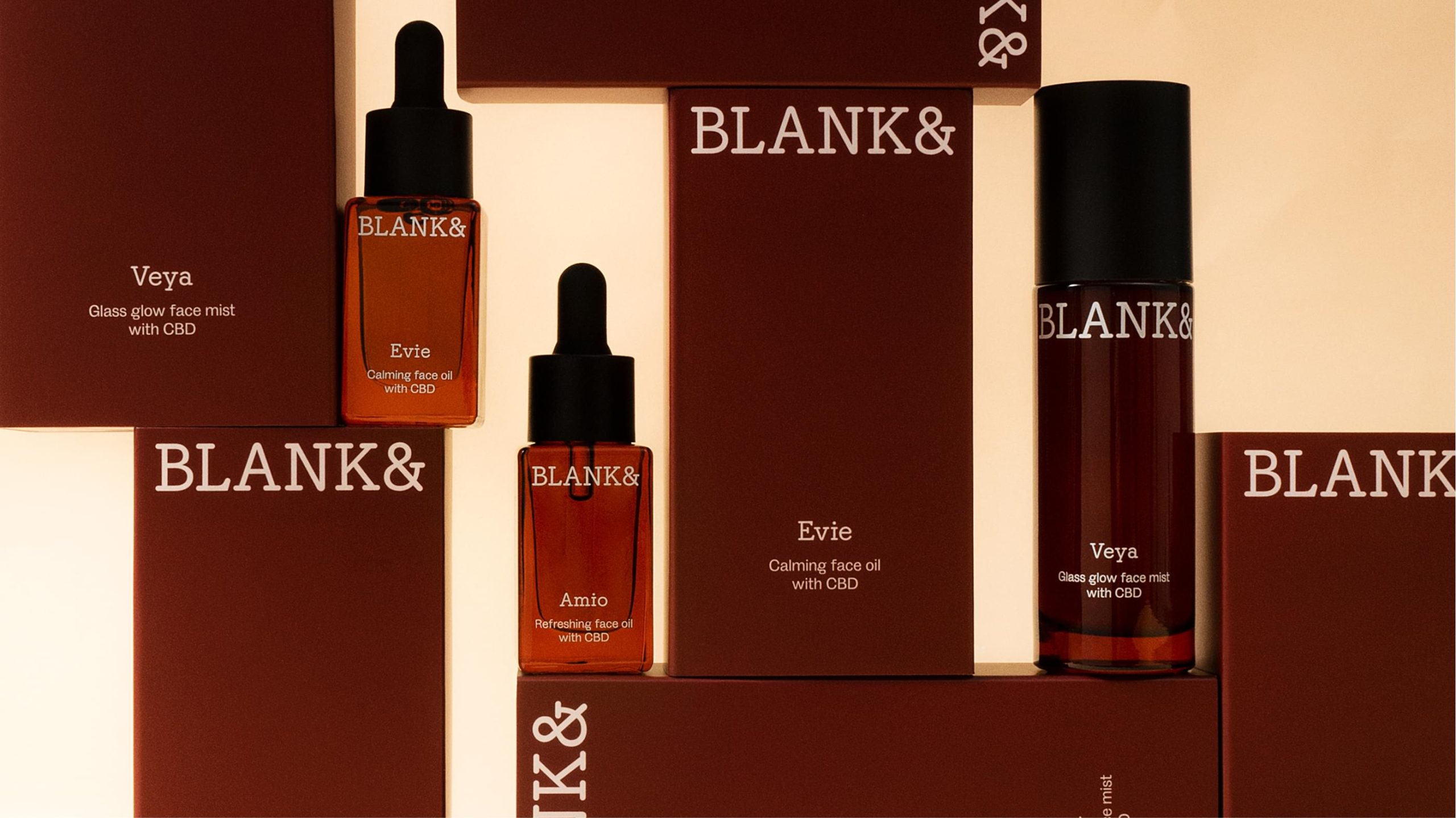 Blank& skincare products—Evie face oil, Amio face oil, and Veya face mist—displayed on stepped dark red branded boxes.