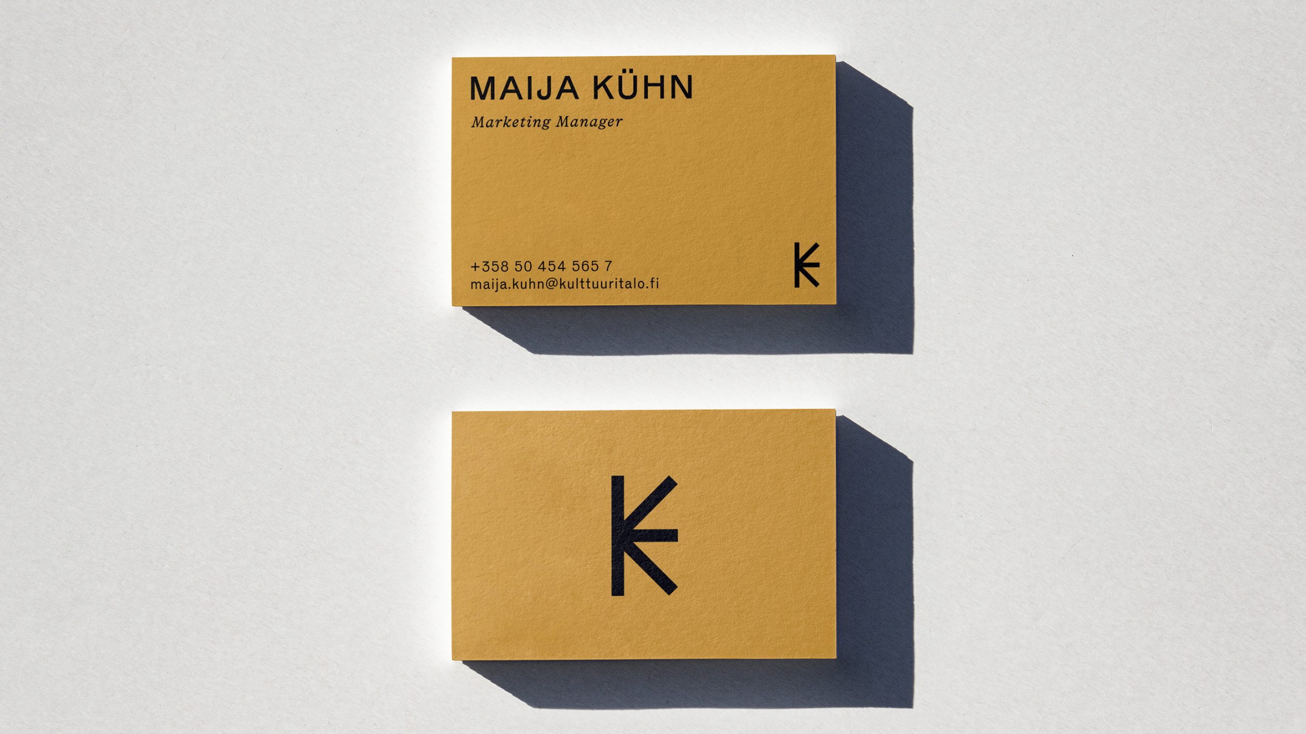 Kulttuuritalo business cards in yellow with black typography, showing front and back designs with a minimal K logomark.