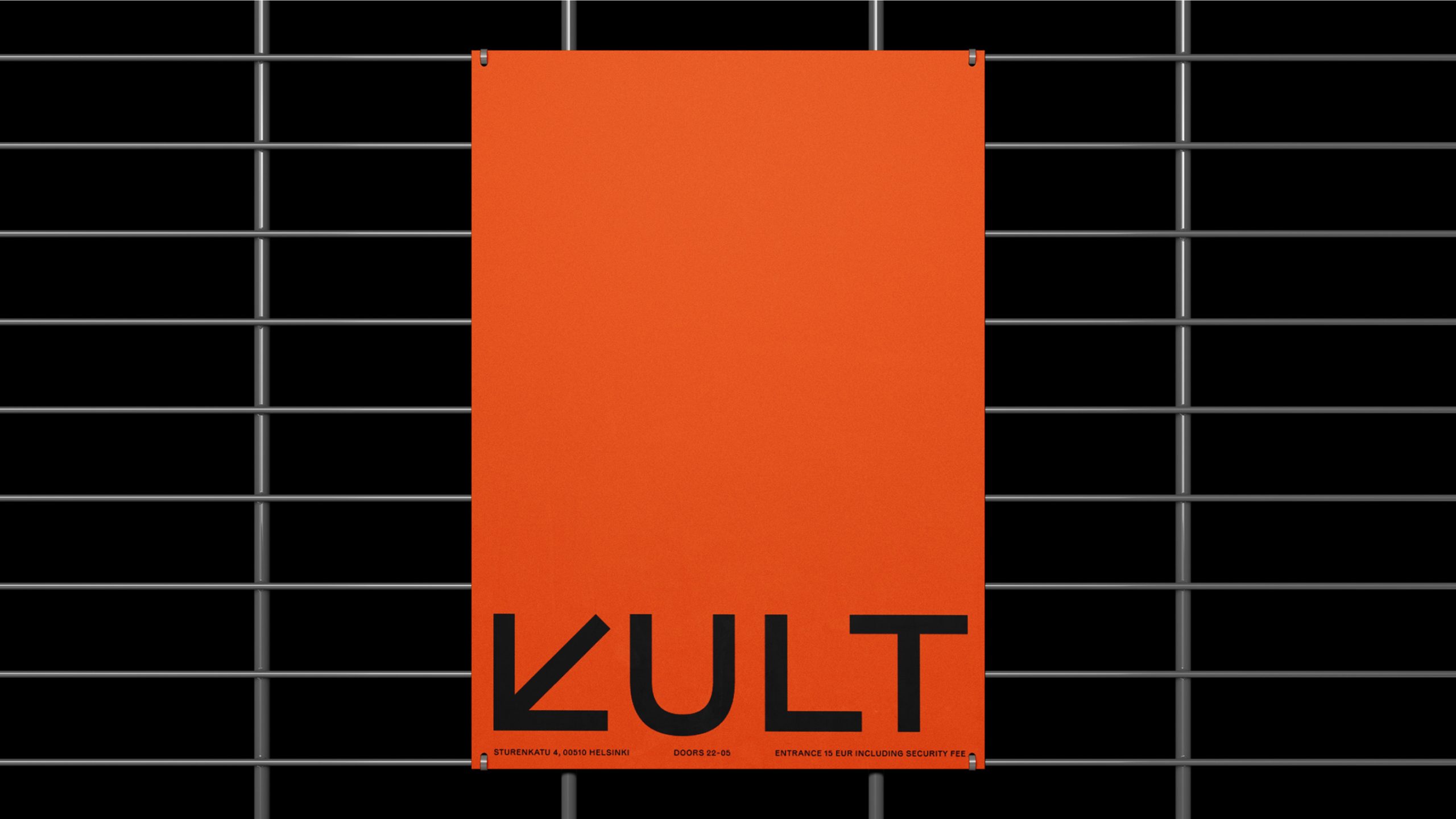 Orange KULT poster hung on metal grid fence, bold black geometric wordmark at bottom with Helsinki venue details.