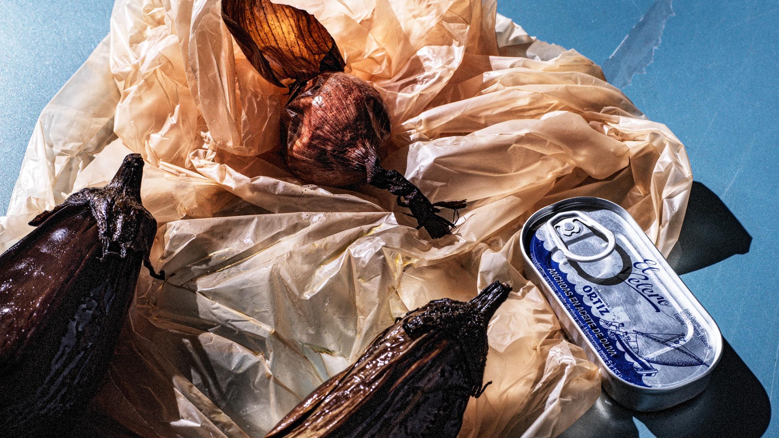 Charred eggplant, roasted onion, and Ortiz anchovy tin on crinkled parchment for Sitko Pizza branding by Werklig.
