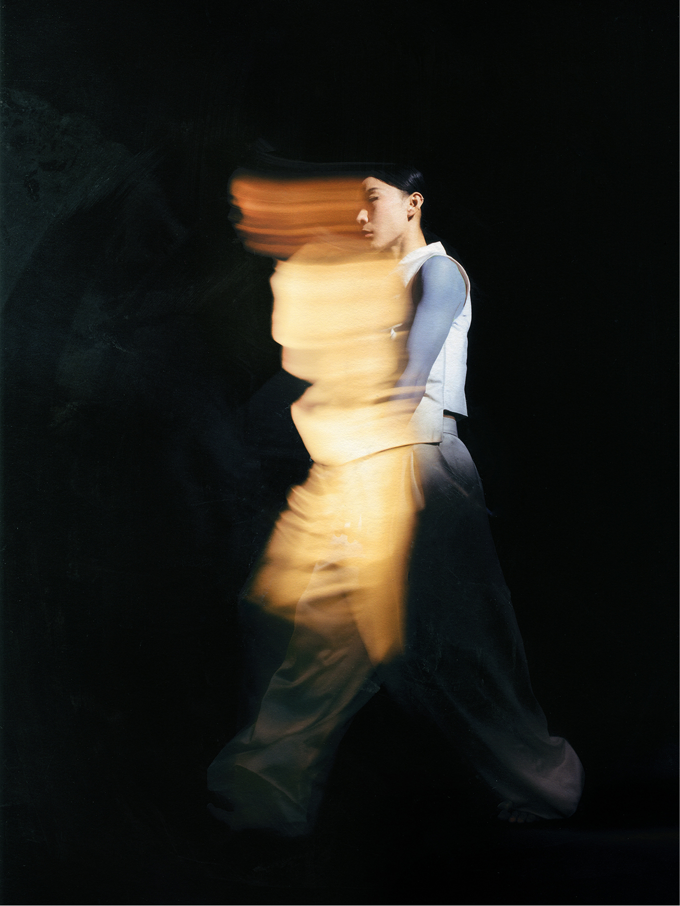 Dancer captured with motion blur and warm light streaks against a dark background for Tero Saarinen Company.