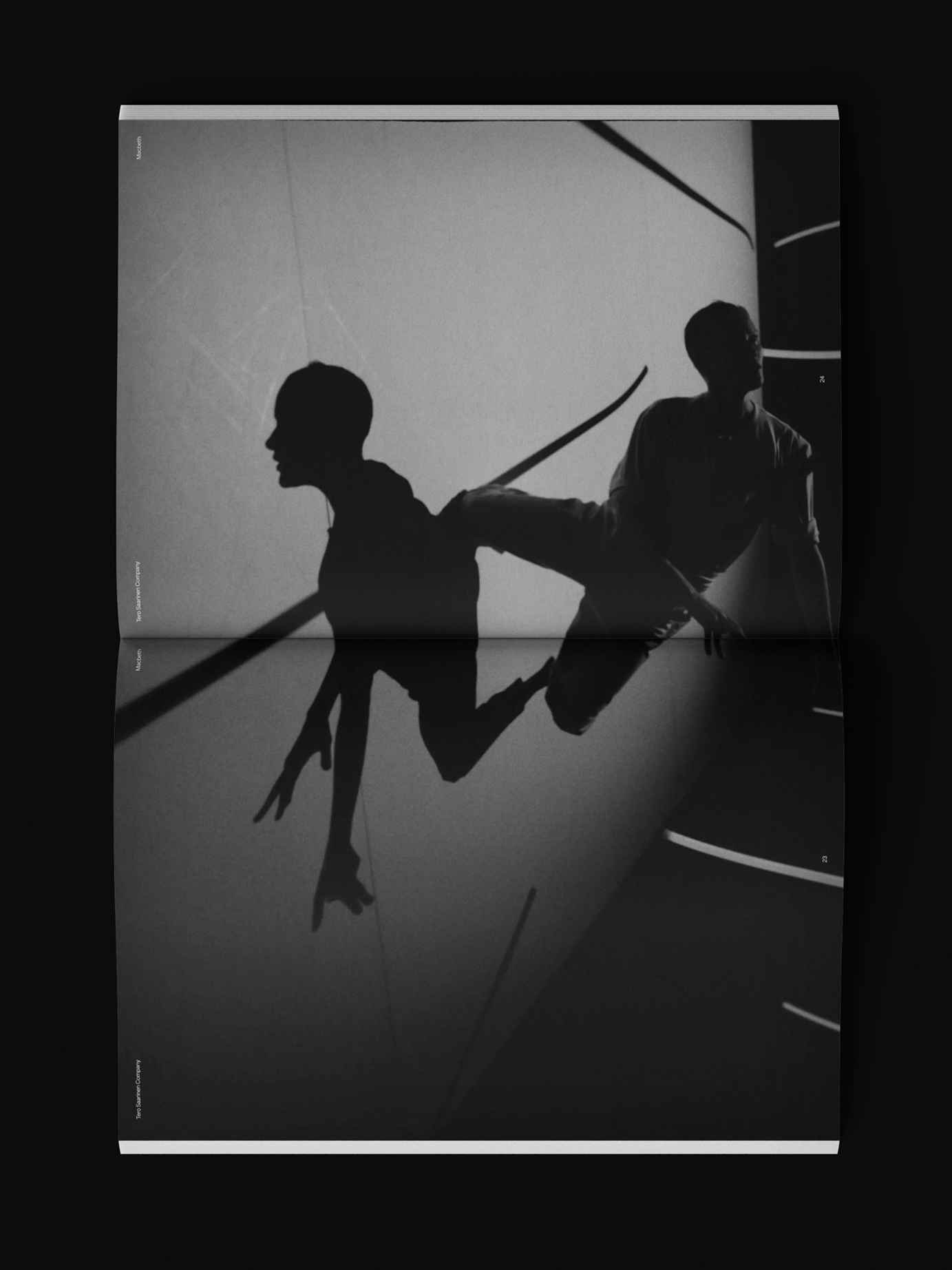 Silhouettes of two dancers and their reflections on a glossy floor, from Tero Saarinen Company's editorial print material.