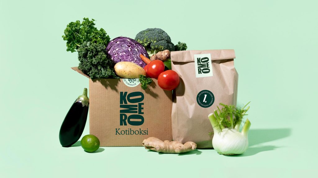 Komero Kotiboksi delivery box and bag overflowing with fresh vegetables.