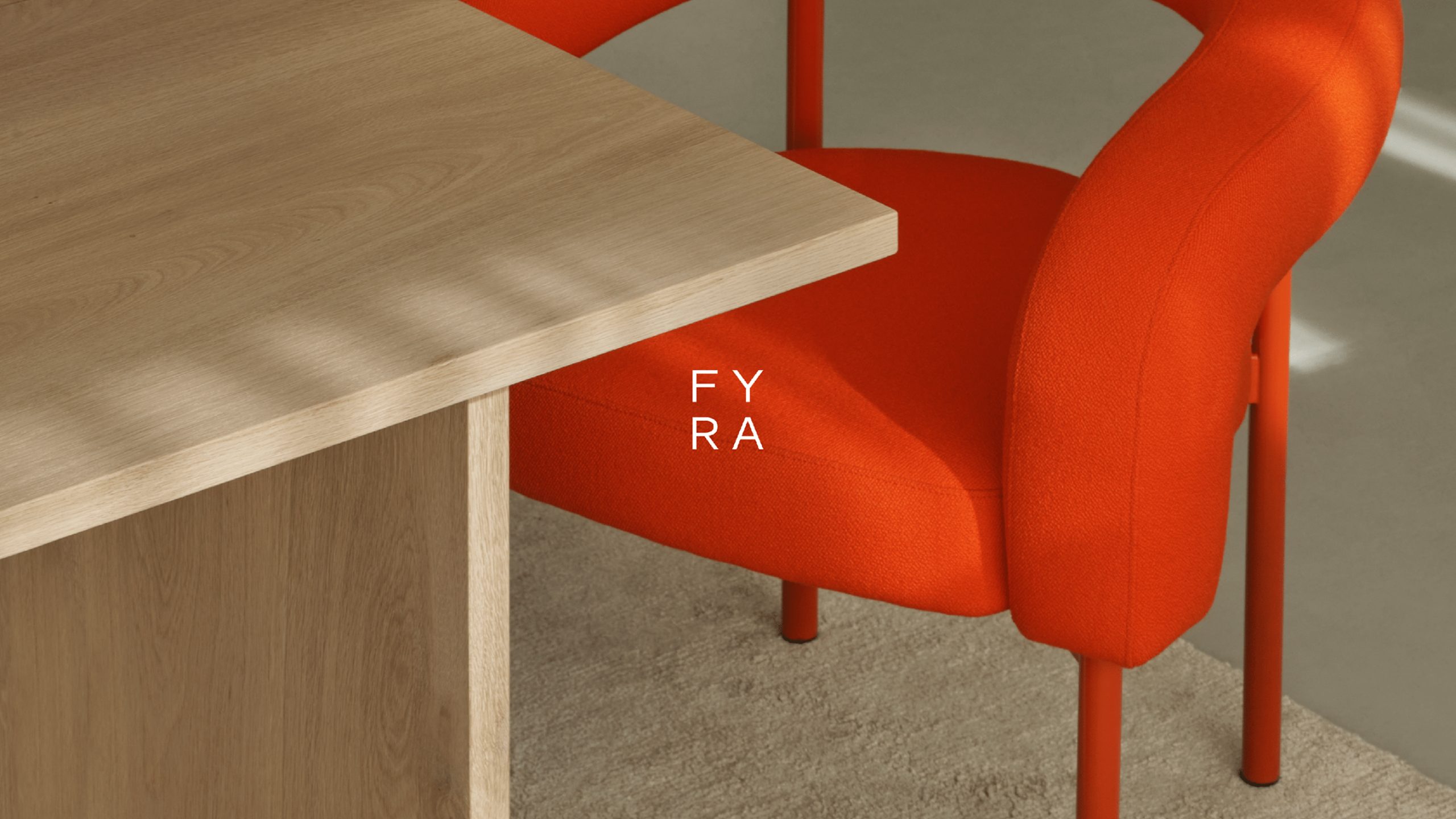 Fyra brand identity: vibrant orange upholstered chair with matching metal legs alongside a light oak wood table on a neutral carpet.