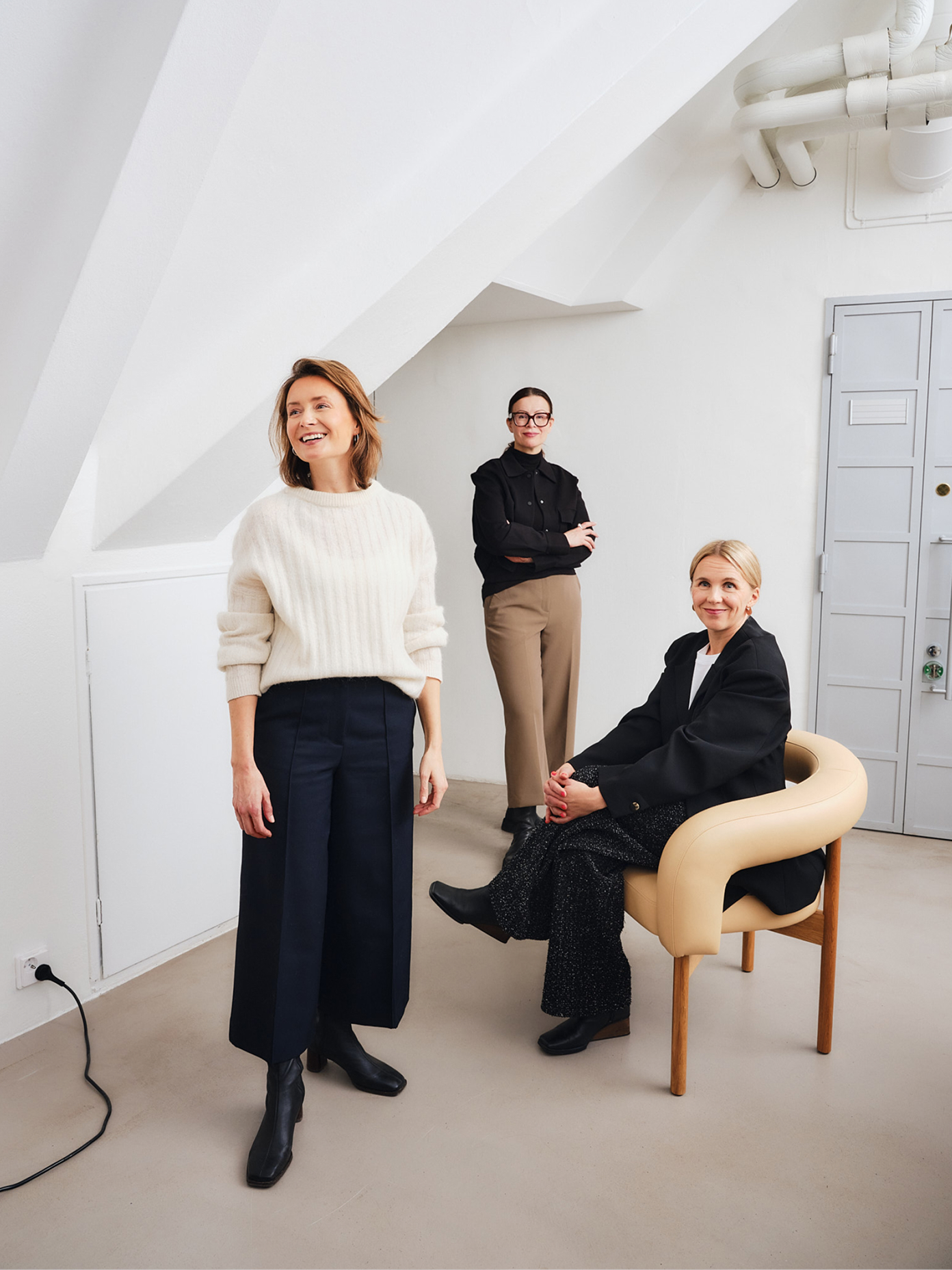 Three founders in minimalist black and neutral outfits posed in a bright white studio space for Fyra branding project.