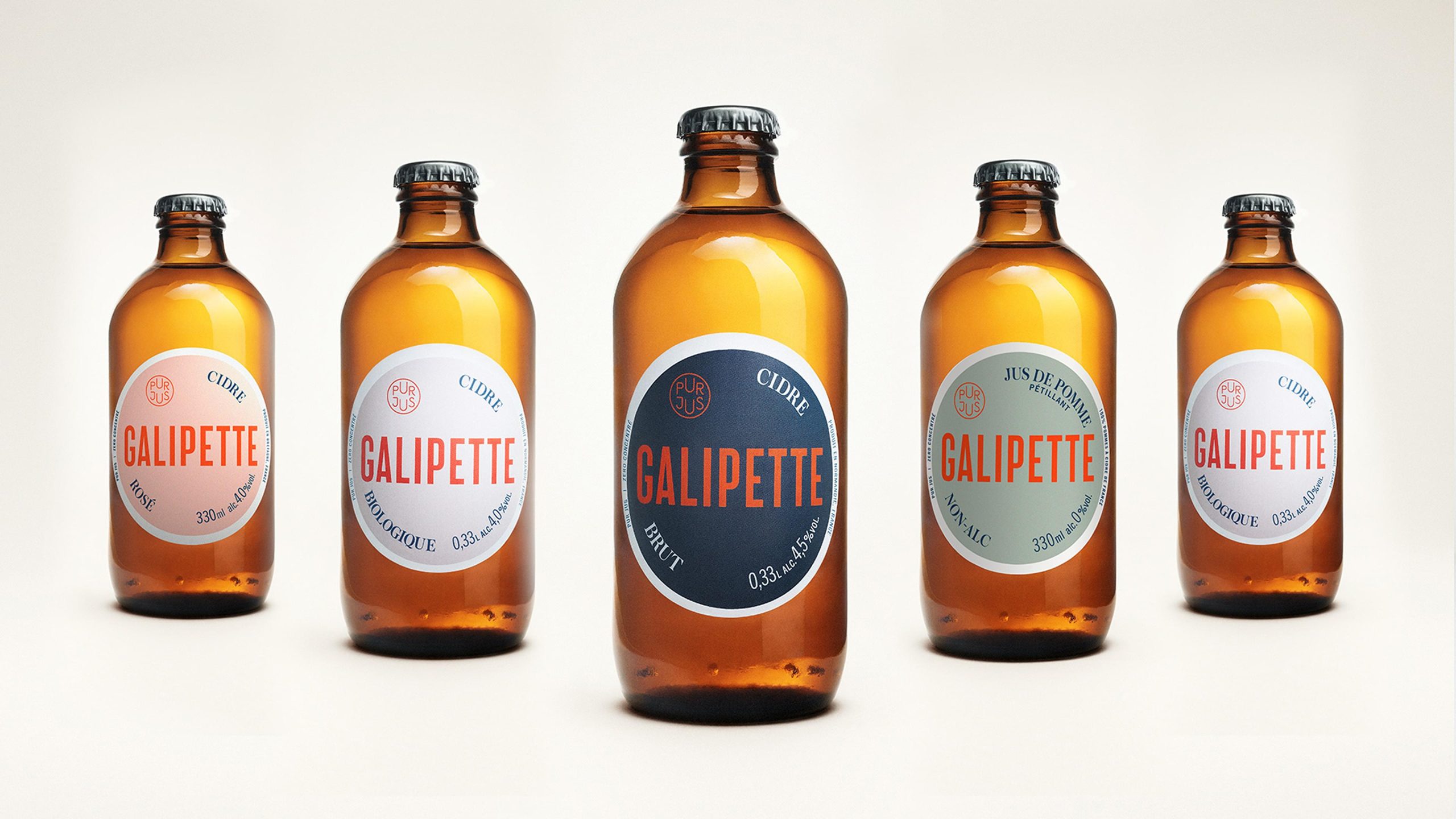 Five Galipette cider bottles with circular labels in pink, white, navy, sage, and white.