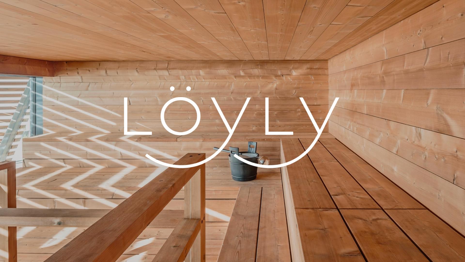 Löyly sauna interior with warm wooden benches and a water bucket, overlaid with the brand's white logo.