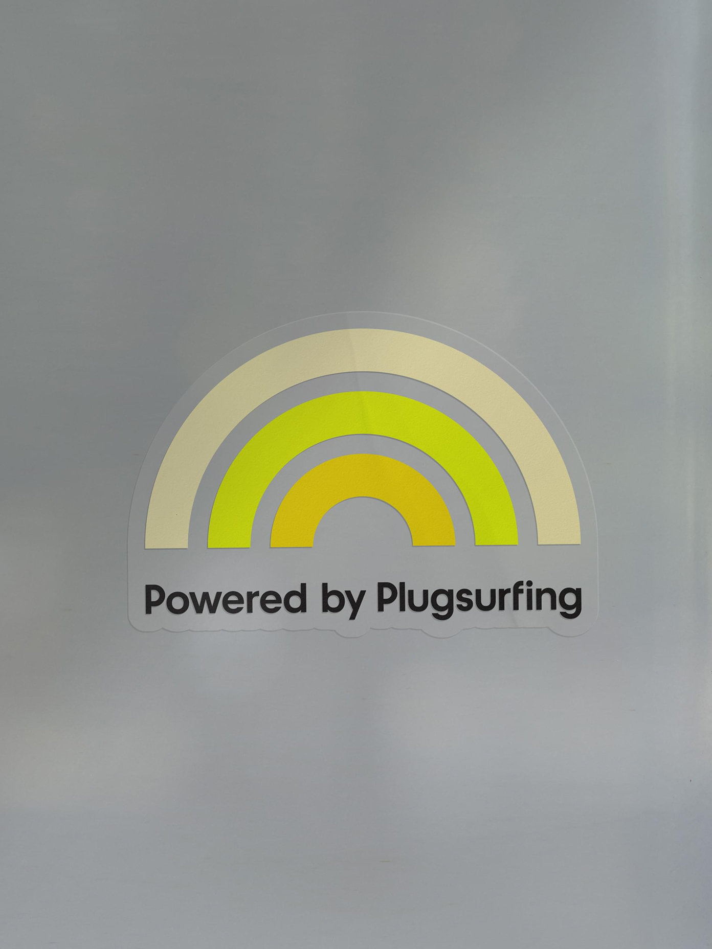 Plugsurfing sticker featuring a yellow-toned rainbow arc logo.