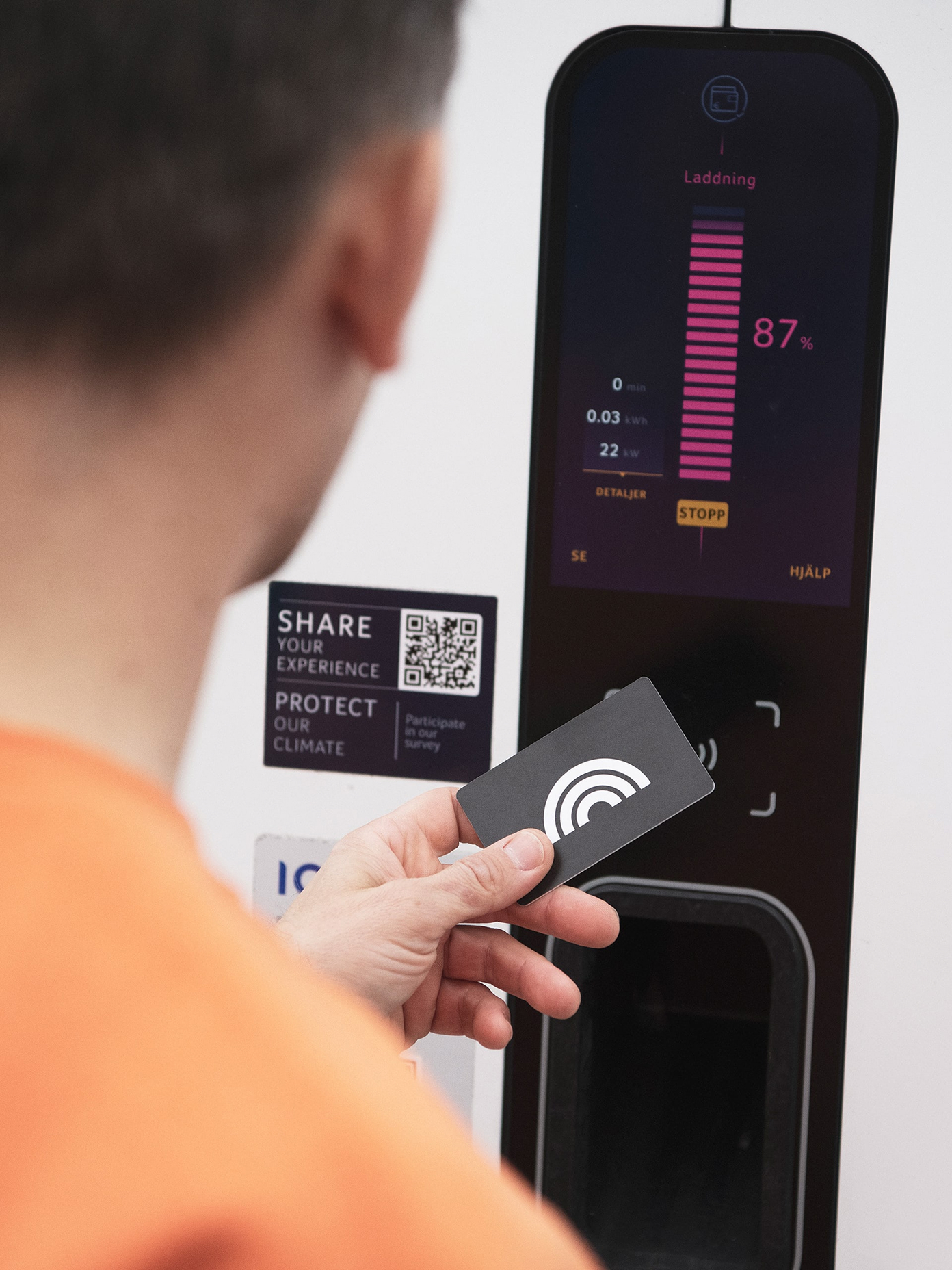 Person tapping a Plugsurfing card on an EV charging station.