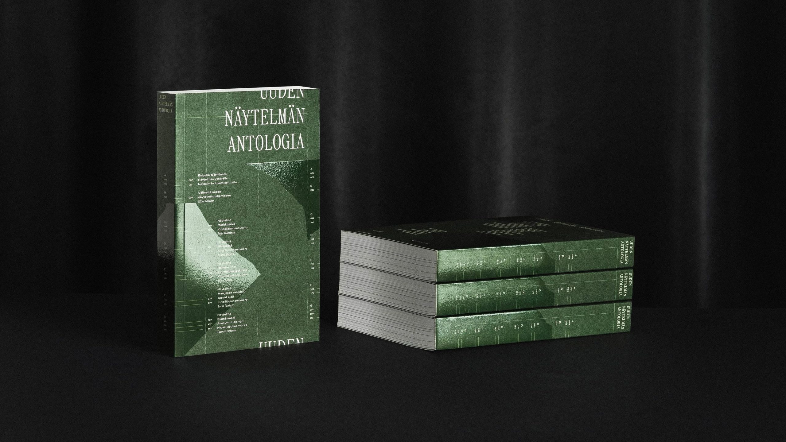 Uuden Näytelmän Antologia books with dark green covers displayed upright and stacked against a black draped background.