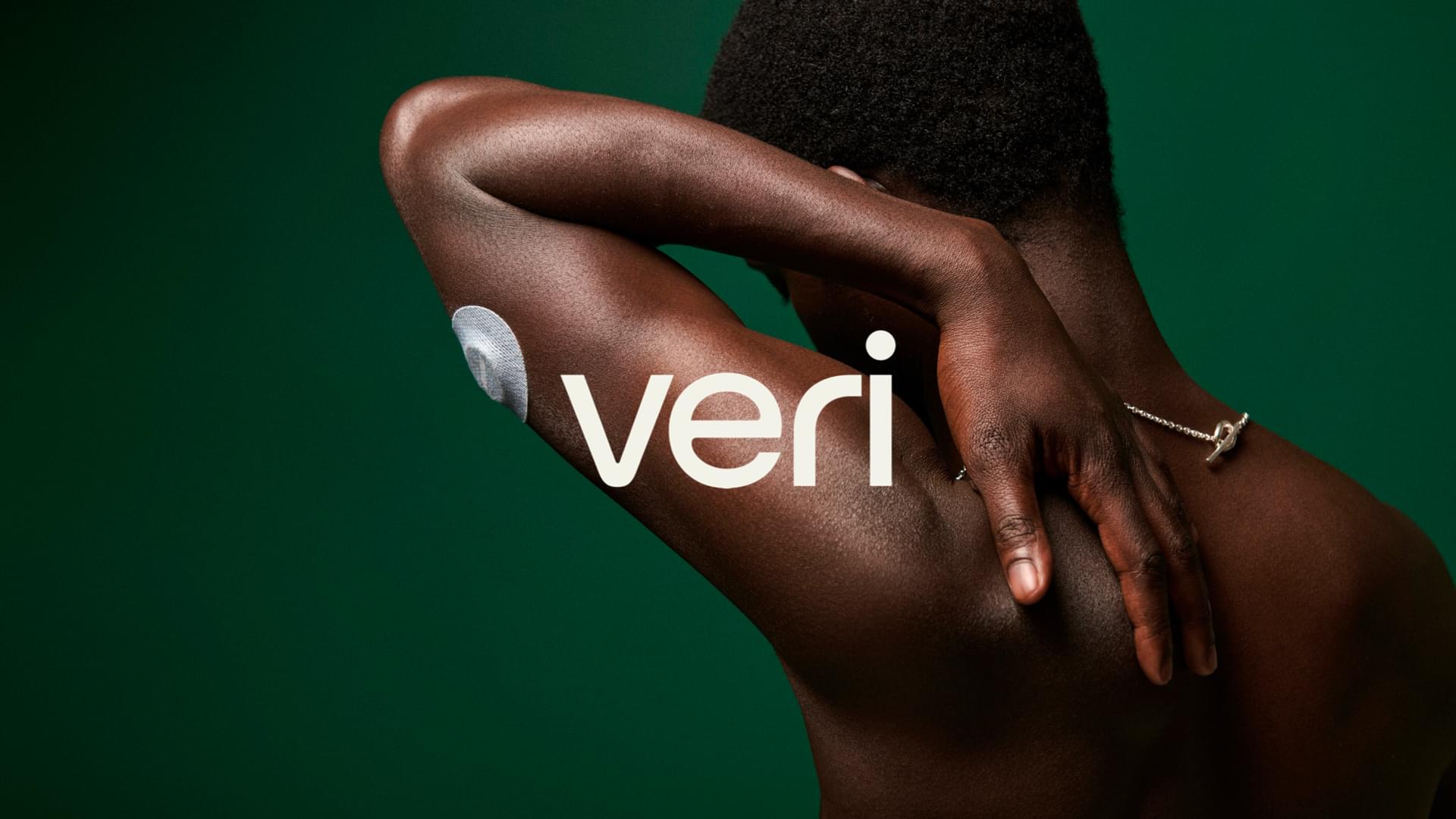 Veri CGM sensor patch on upper arm against deep green background, with Veri brand logo overlaid in white.
