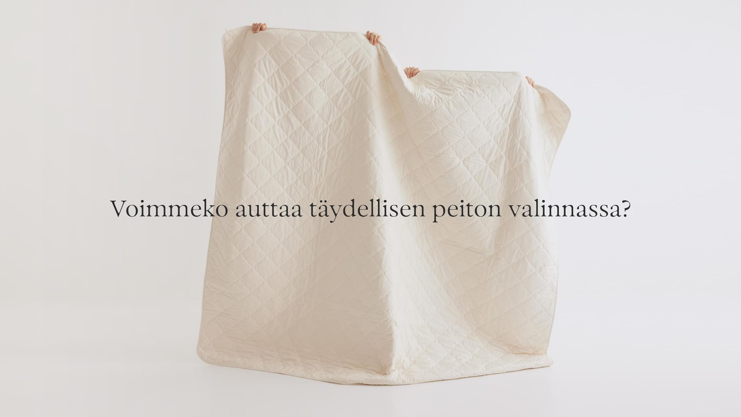 Hands holding up a cream quilted duvet against a white background.
