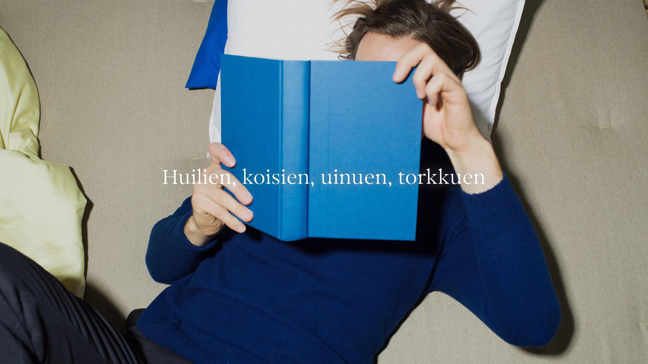 Person lying down reading a blue book.