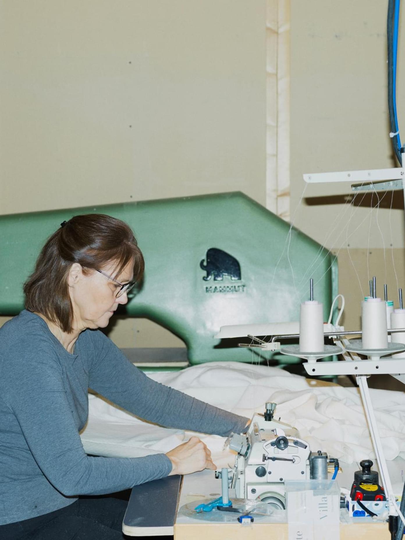 A seamstress operates an industrial sewing machine at a Villa & Peite textile workshop.